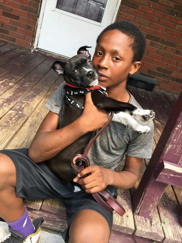 Teenage boy holding a small, black and white puppy