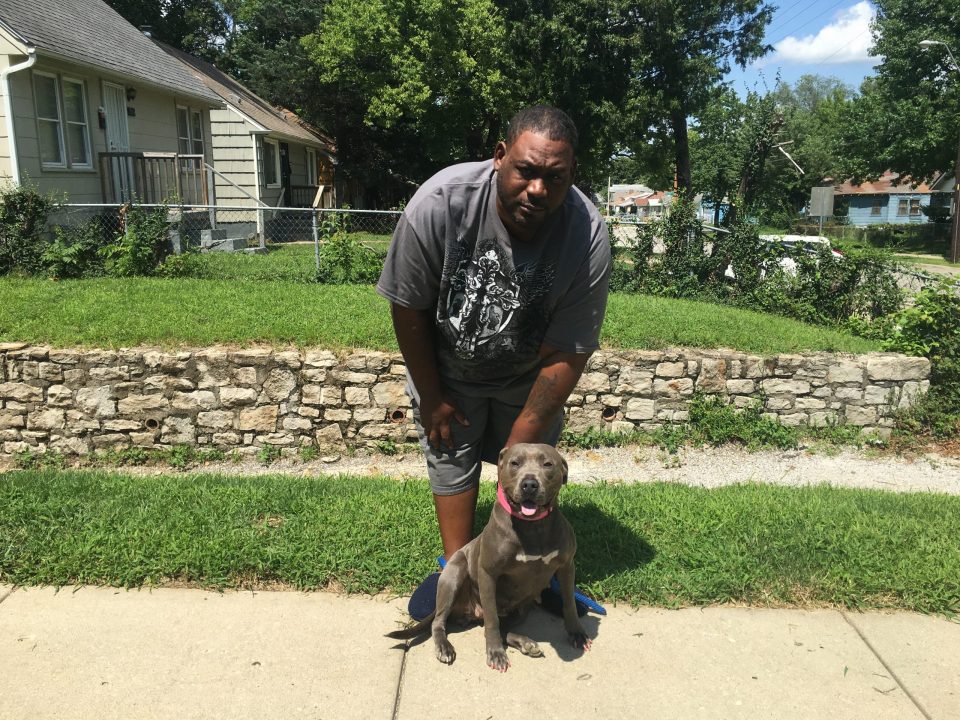 man with pit bull on sidewalk