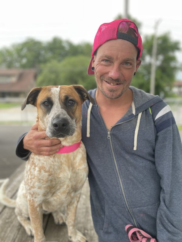 man smiling while hugging his dog