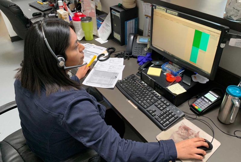 A woman sits at a desk, using a computer.