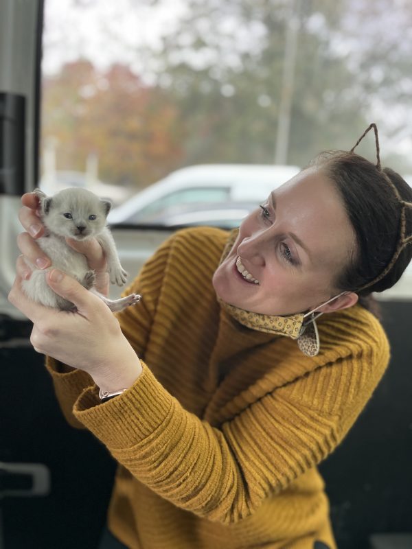 woman smiling while holding young kitten