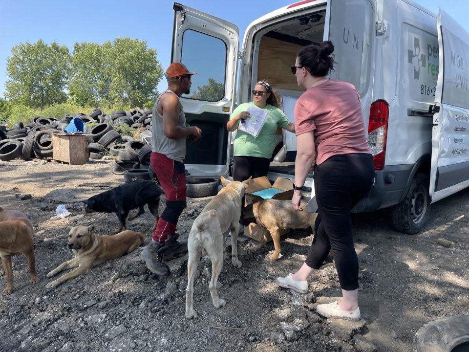 pet outreach team giving resources to man who owns dogs at a junkyard