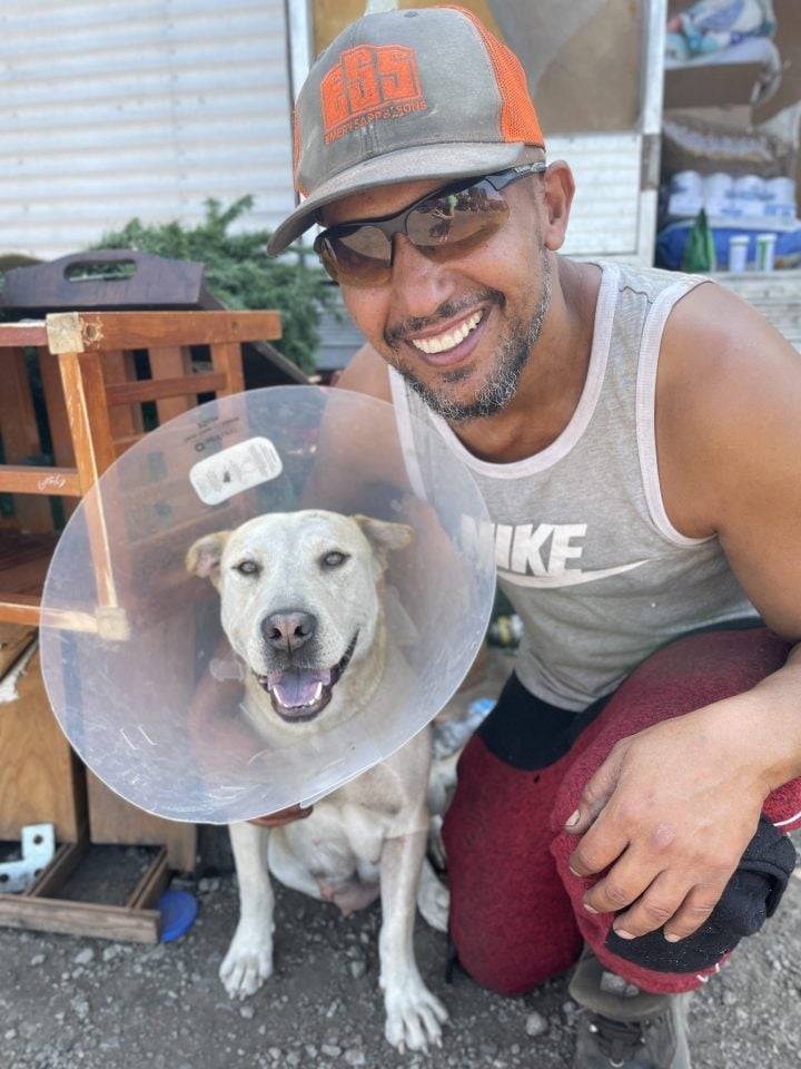 Man smiling and hugging his dog after surgery