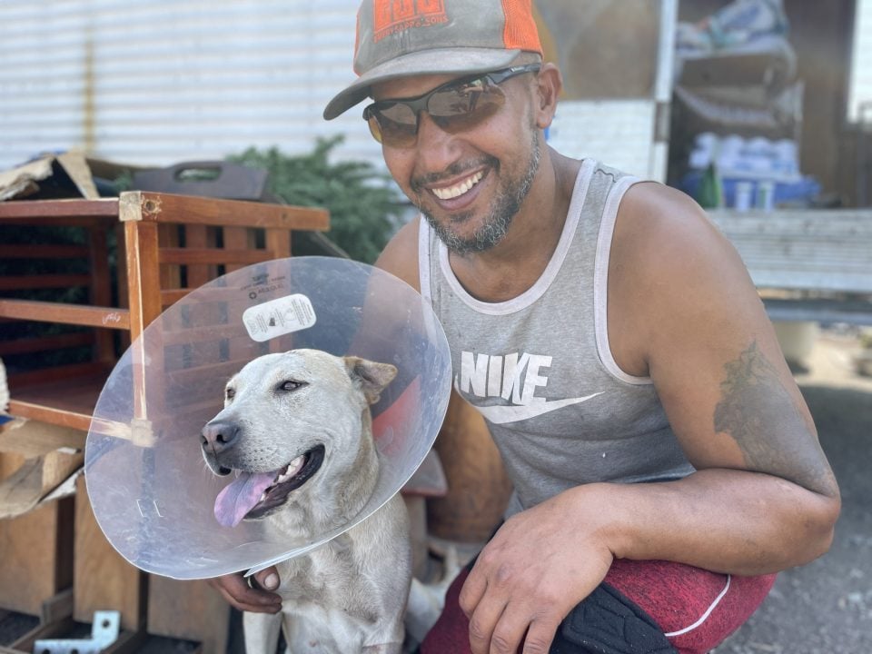 Man smiling and hugging his dog after surgery