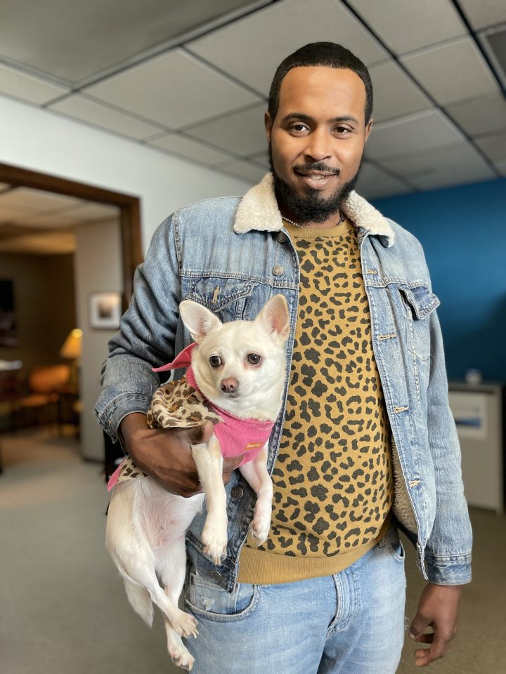 man smiling at the camera while holding his chihuahua