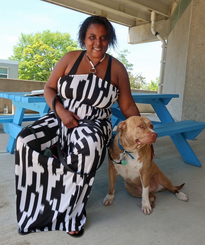 a woman in a black and white dress sits next to her dog