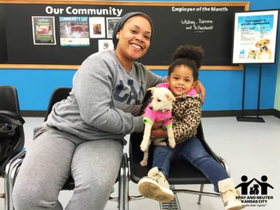 A woman and her daughter hold their puppy and smile at the camera