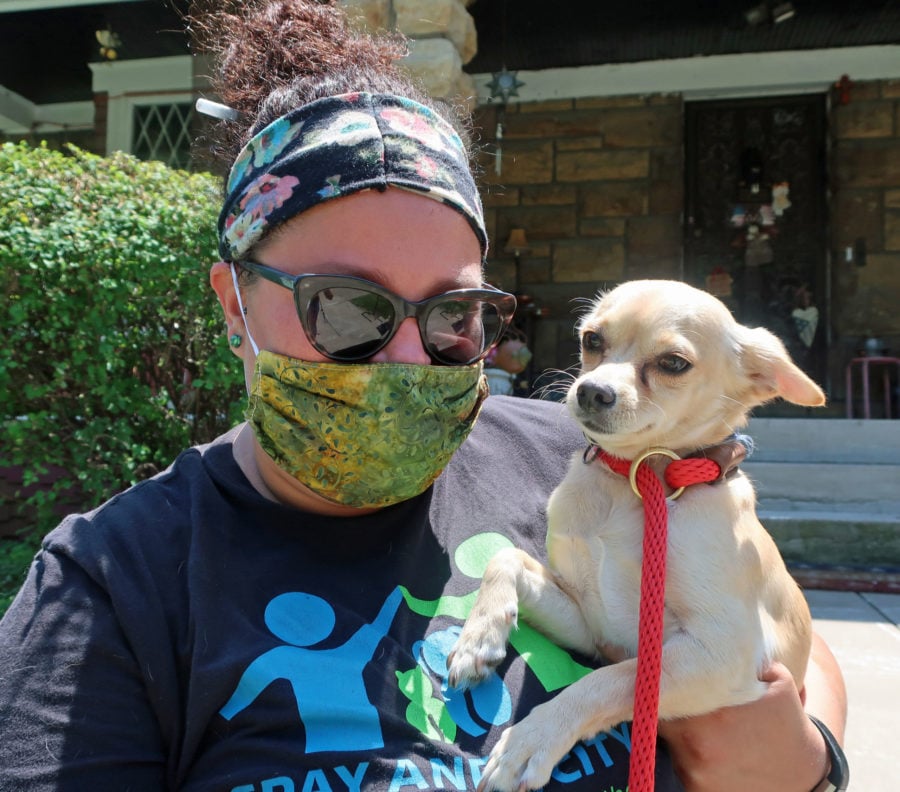 a woman wearing a protective mask holds a dog