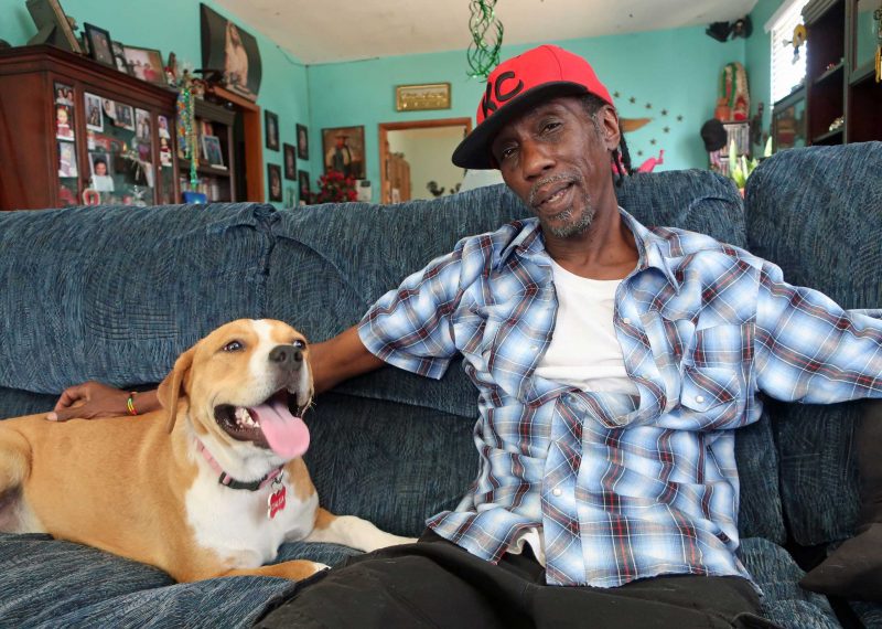 A man and his dog sit on the couch together