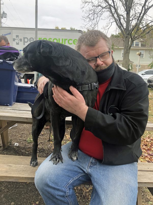 Man hugging his service dog tightly with his eyes closed