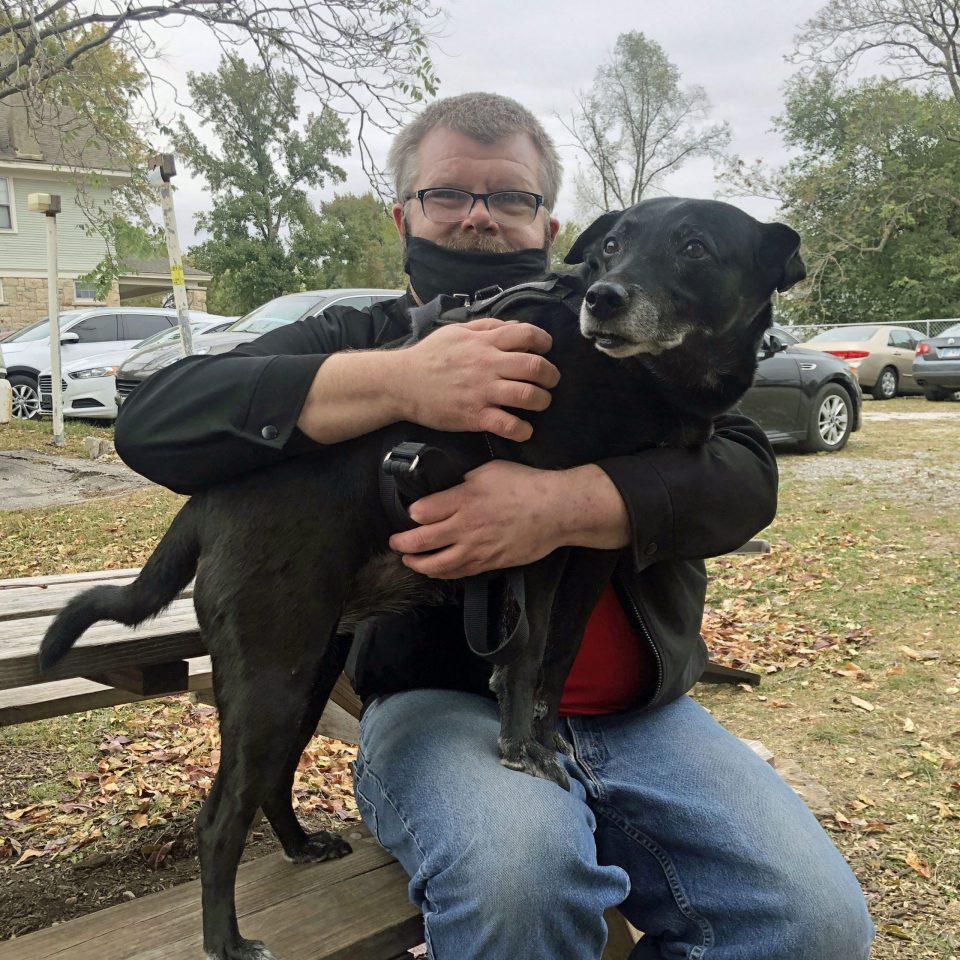 Service dog on man's lap at picnic tables