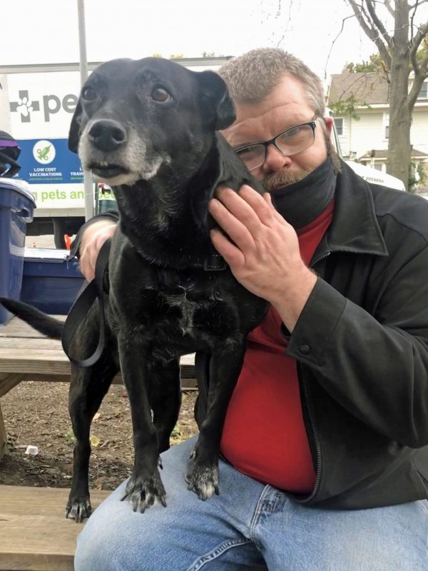 Man and service dog hugging while smiling at the camera