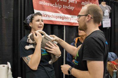 Two volunteers spend time with a puppy.