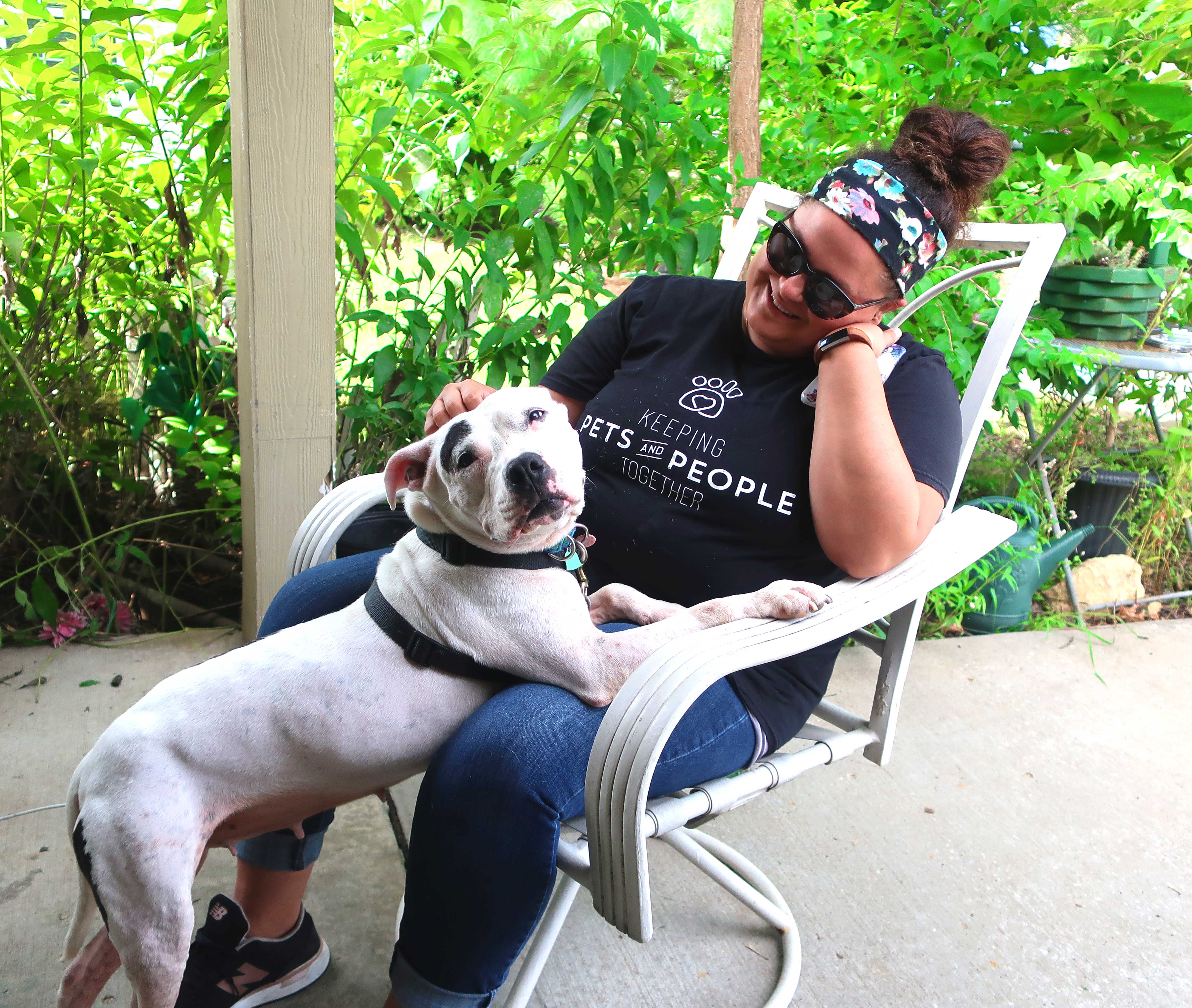 A dog rests the front half of her body on the lap of a woman.