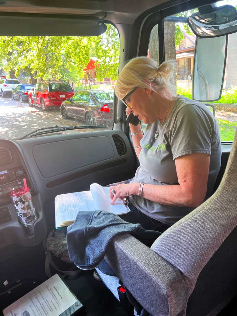 Ramona sits in the front seat of the RV, working with clinic employees to set up spay appointments for a client.