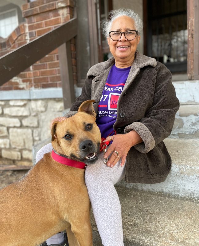 A woman and her dog sit on the front steps of a building